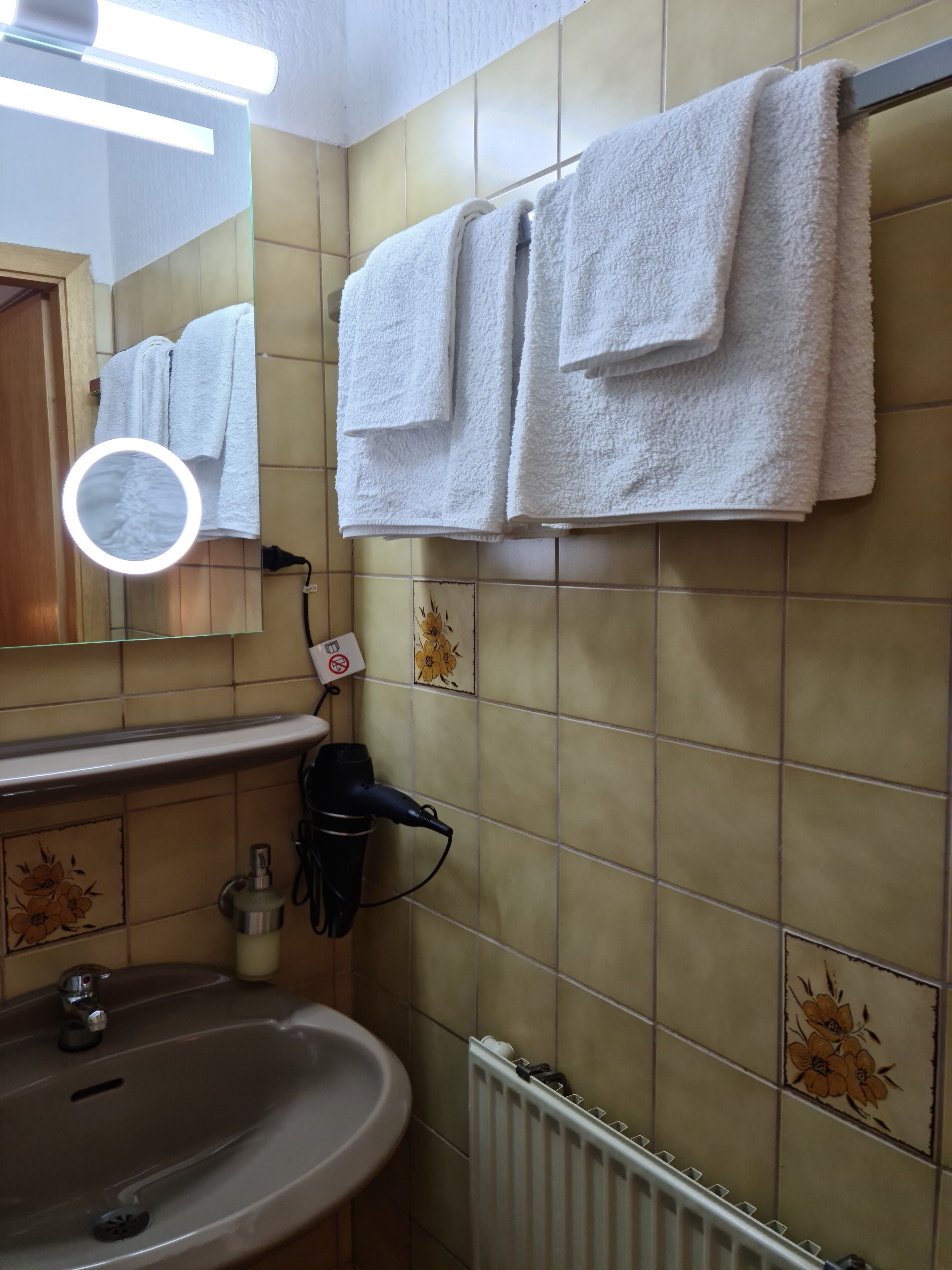 A bathroom with a sink, mirror, and towels hanging on the wall.