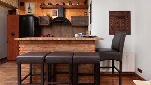 A kitchen with a brick island, black stools, and a black chair. - Comfortable Apartment in Gdynia | 2 Bedrooms | Parking (Gdynia)