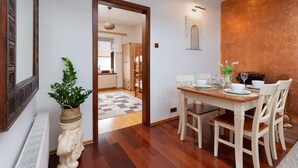 A dining area with a wooden table set for four, white chairs, and a potted plant. - Comfortable Apartment in Gdynia | 2 Bedrooms | Parking (Gdynia)