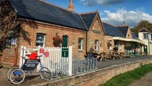 A traditional brick building with a sloped roof, a white picket fence, and a bicycle parked outside. - Freshwater - Hot Tub - Pet Friendly - Garden (Freshwater)