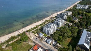 Luftaufnahme einer Küstenlandschaft mit Strand, Gebäuden und einer Straße.