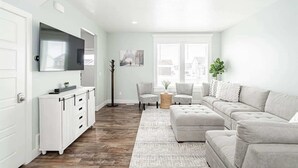 Una sala de estar con un sofá blanco, un televisor y un mueble.