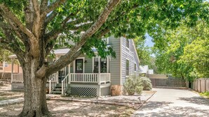 A single-story house with a porch, a tree in front, and a driveway.