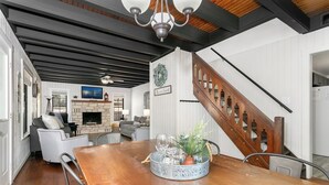 A dining area with a wooden table, chairs, a fireplace, and a staircase.