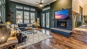 A modern living room with a stone fireplace, dark green walls, and a large window. - 5Bdrm 3Ba Posh Lake Texoma Home (Pottsboro)
