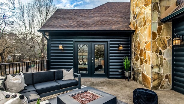 A log cabin with a stone exterior, a black exterior, and a fire pit in the center. - 5Bdrm 3Ba Posh Lake Texoma Home (Pottsboro)