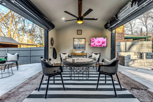 A covered patio area with a round table and chairs, a ceiling fan, and a TV mounted on the wall. - 5Bdrm 3Ba Posh Lake Texoma Home (Pottsboro)