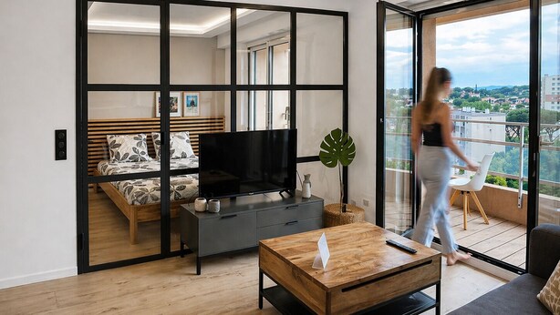 A modern living room with a sofa, a coffee table, a TV, and a balcony with a view. - VACATELLA - LES PINS ENSOLEILLÉS / Contemporary apartment with sea view (Sainte-Maxime)