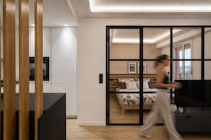 A modern bedroom with a bed, a TV, and a sliding door leading to a balcony.