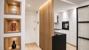 A modern kitchen with wooden cabinetry, a black countertop, and a built-in oven. - VACATELLA - LES PINS ENSOLEILLÉS / Contemporary apartment with sea view (Sainte-Maxime)