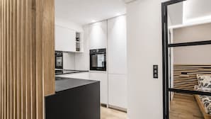 A modern kitchen with white cabinets, a black countertop, and a built-in oven. - VACATELLA - LES PINS ENSOLEILLÉS / Contemporary apartment with sea view (Sainte-Maxime)