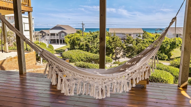 A hammock on a wooden deck overlooking a residential area with houses and a view of the ocean. - Private Coastal Haven - 2nd Row, Spectacular views (Emerald Isle)