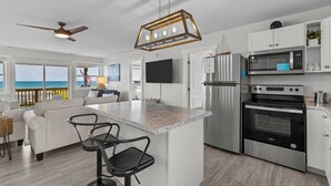 A modern kitchen with a large island, stainless steel appliances, and a view of the ocean. - Private Coastal Haven - 2nd Row, Spectacular views (Emerald Isle)