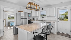 A modern kitchen with a large island, stainless steel appliances, and a pendant light. - Private Coastal Haven - 2nd Row, Spectacular views (Emerald Isle)