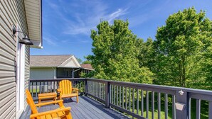Une terrasse en bois avec des chaises, une rambarde et une maison en arrière-plan.