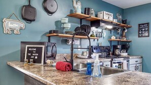 Une cuisine dotée de plans de travail en granit, d’une cuisinière, d’un évier, ainsi que de divers ustensiles et appareils de cuisine.