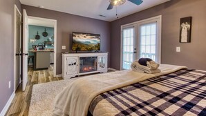Une chambre avec un lit, un ventilateur de plafond, une cheminée et une vue sur la cuisine.