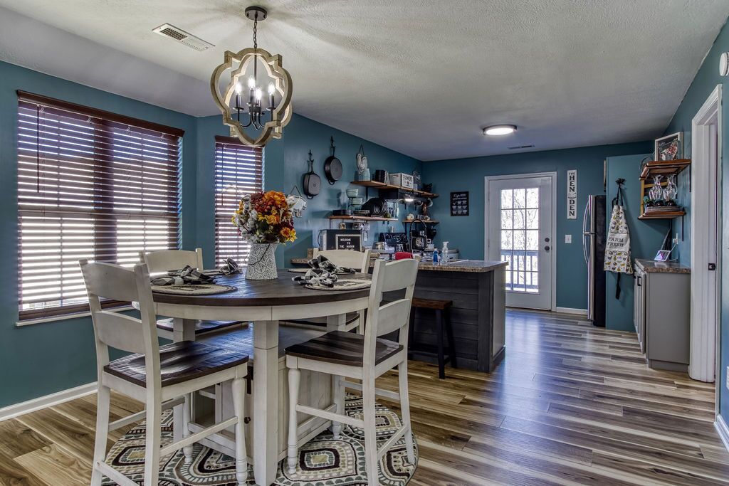 A dining area with a round table, chairs, and a chandelier.