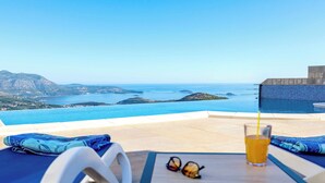 Una terraza soleada con piscina, una mesa con una bebida y un par de gafas de sol.