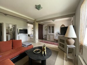 A living room with a sofa, a coffee table, a TV, a cabinet, and a lamp.