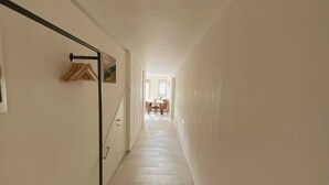 A narrow hallway with a coat rack, a dining area with chairs and a table at the end. - SUPERIOR SUITE, Verona | 1K_HOME (Bosco Chiesanuova)