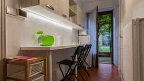 Una cocina compacta con una encimera blanca, un adorno verde y una silla de madera.