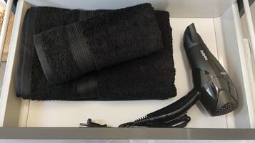 Ein Badezimmer mit einem weißen Waschbecken, einem schwarzen Handtuch und einem Föhn.