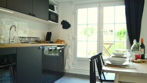 Une cuisine moderne avec des meubles de couleur sombre, un lave-vaisselle et une fenêtre avec des rideaux.