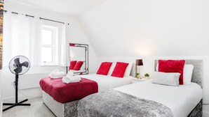 A hotel room with two beds, a large mirror, a standing fan, and a window with curtains. - Comfortable 2BR Apartment in Bedford (Bedford)