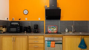 Una cocina equipada con microondas, cafetera, tostadora y un reloj en la pared.