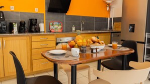 Una cocina moderna con paredes anaranjadas, una mesa de comedor de madera y diferentes alimentos para el desayuno.