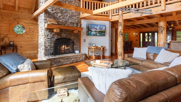 A cozy log cabin interior with a stone fireplace, leather sofas, and a wooden staircase. - Authentic Log Cabin in the Mountains (Seven Devils)