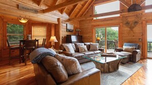 A spacious wooden cabin with a large living area featuring a sofa set, a glass coffee table, and a television. - Authentic Log Cabin in the Mountains (Seven Devils)