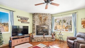 A living room with a stone fireplace, a flat-screen TV, and a leather sofa. - Hudson Hideaway, your home away from home (June Lake)