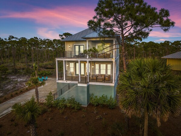 A two-story house with a balcony, surrounded by trees and a natural landscape. - Paradise | Oceanview, Hottub, Shuffleboard, Bikes, Beach, Pool (Port St. Joe)