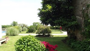 A garden with a variety of plants and a stone structure. - Beautiful Gite with pool and jacuzzi 6 pers 3 bedrooms (Nantille)