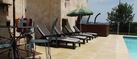A poolside area with lounge chairs, a table, and a bar area.