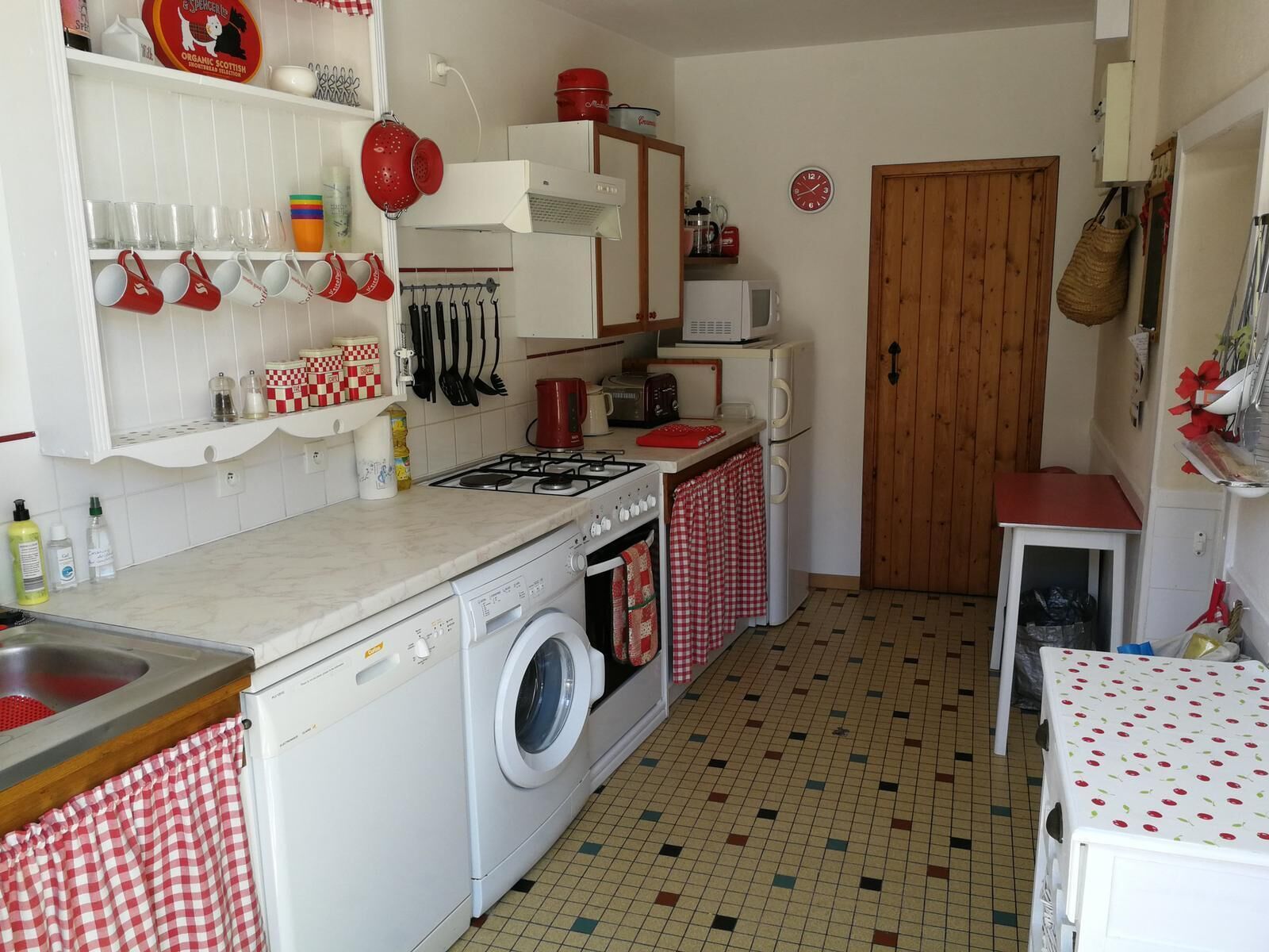 A compact kitchen with a gas stove, a washing machine, and a microwave.