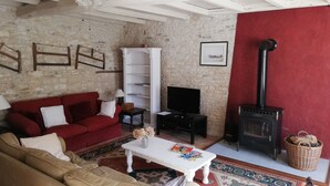 A living room with a red sofa, beige sofa, white coffee table, TV, and a fireplace. - Beautiful Gite with pool and jacuzzi 6 pers 3 bedrooms (Nantille)