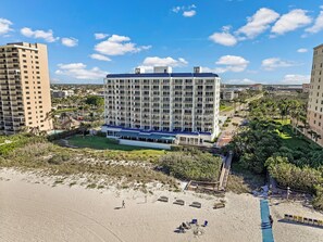 A high-rise hotel with multiple balconies, a pool area, and a beach view.