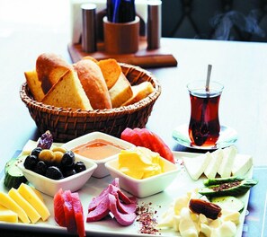 Una mesa con diversos alimentos, como pan, queso, aceitunas y una taza de té.