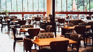 A restaurant with wooden tables and chairs, large windows, and a central column. - Grand Selale Hotel (Çayeli)