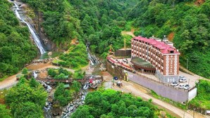 A hotel with a red roof, located in a lush green valley with a waterfall. - Grand Selale Hotel (Çayeli)