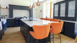 Une cuisine moderne avec des meubles de couleur sombre, un grand îlot central et des tabourets de bar orange.