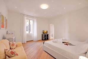 Une chambre d’hôtel avec un lit, un canapé, une télévision et une fenêtre.