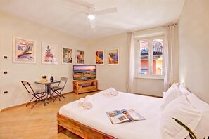 Een hotelkamer met een bed, een bureau met stoel, een televisie en kunstwerken aan de muur.