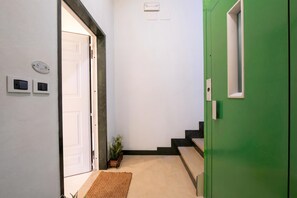 Um corredor com uma porta verde, uma porta branca e uma pequena planta.