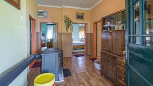 A hallway with a wooden floor, a radiator, a yellow bucket, and a green door. - Traditional Child Friendly Homestead Larva (Velika)