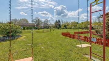 A playground with swings and a red fence.