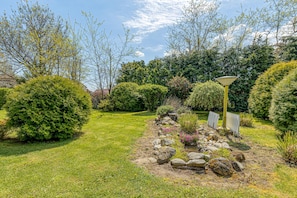 Un jardin agrémenté de divers arbustes, d’un sentier et d’un lampadaire.